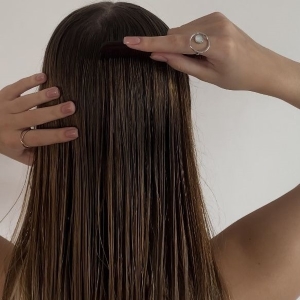 Frau mit frischem Gesicht und Haarpflegeprodukt