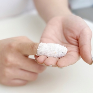 Frau hält bandagierten Finger