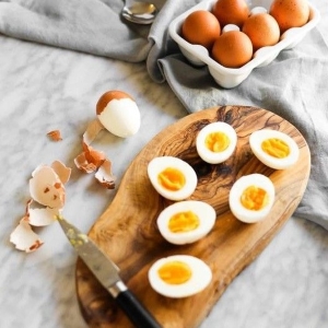 Halved eggs on wooden board